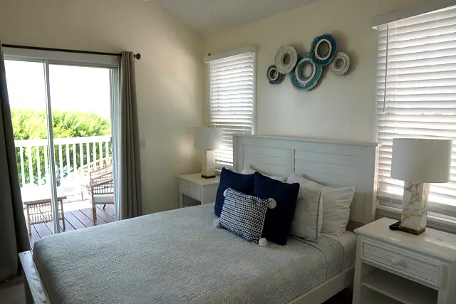 Bedroom at villa 5012 with a queen bed and sliding doors onto the porch above the water