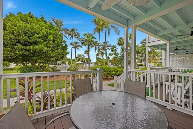Covered porch at villa 5092 with a table, chairs and palms beyond